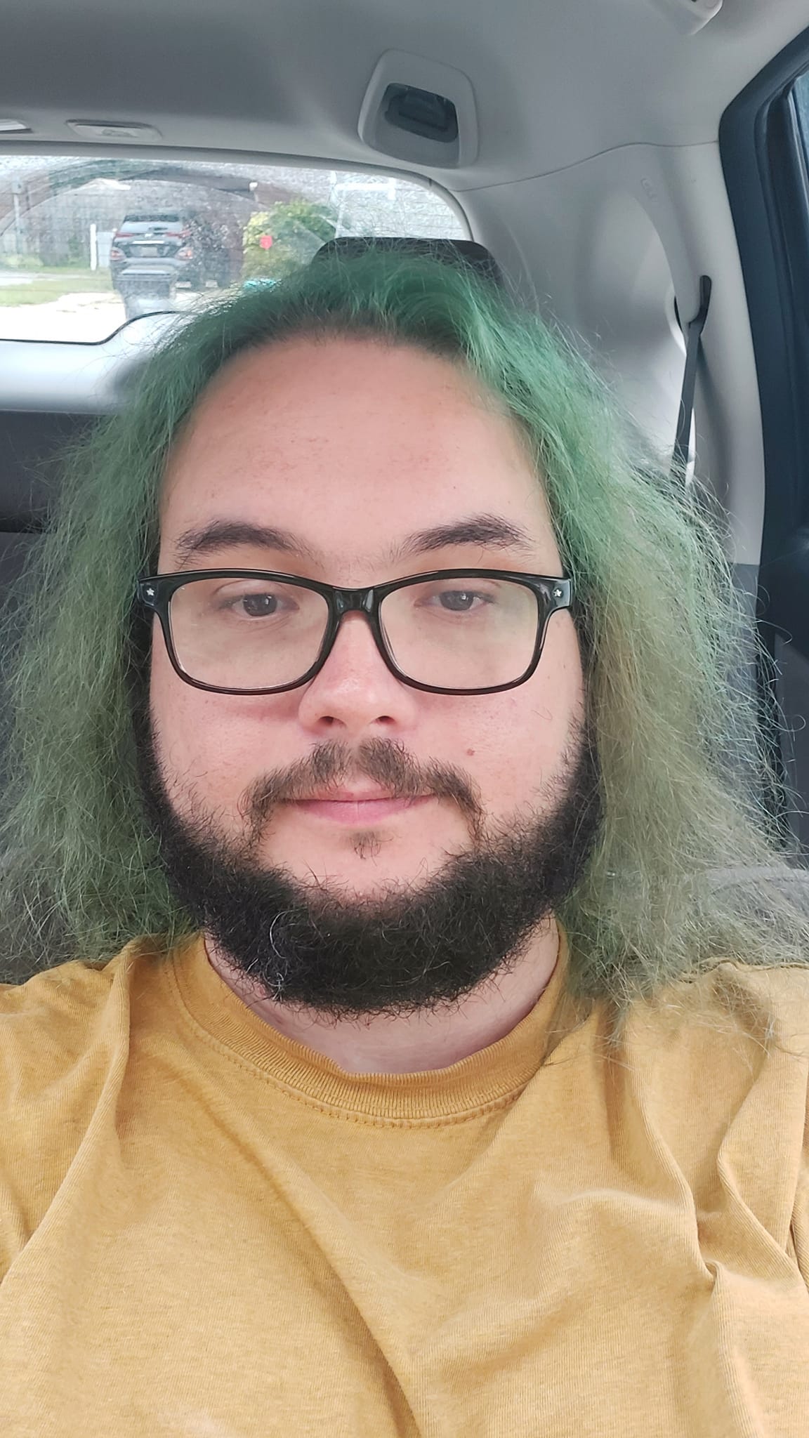 A man with green hair reclines in a car